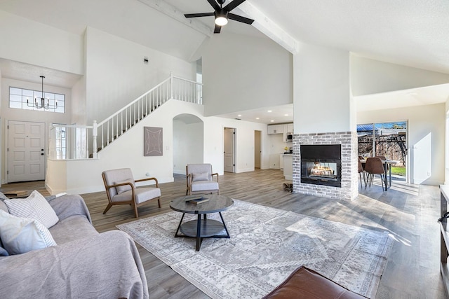 living room featuring light wood-type flooring, a brick fireplace, a healthy amount of sunlight, and beam ceiling