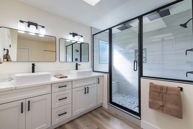 bathroom with hardwood / wood-style flooring, a textured ceiling, vanity, and a shower with door