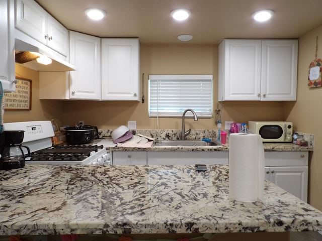 kitchen featuring sink, white range with gas stovetop, and white cabinets