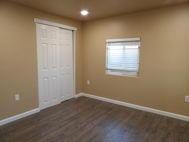 unfurnished bedroom with dark wood-type flooring and a closet