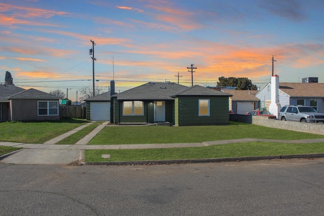 ranch-style house featuring a garage, a shingled roof, fence, concrete driveway, and a front lawn