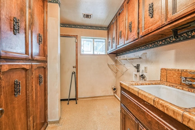 washroom featuring washer hookup, sink, and cabinets