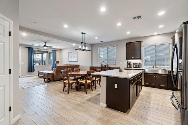 kitchen featuring pendant lighting, sink, stainless steel refrigerator, a center island, and light hardwood / wood-style floors