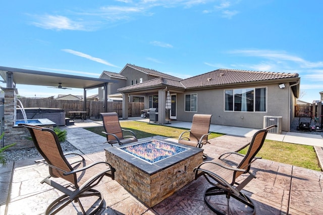 view of patio featuring cooling unit, a hot tub, and an outdoor fire pit