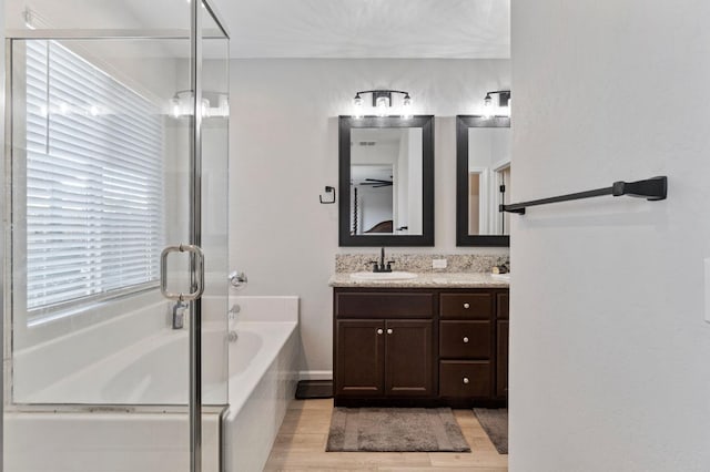 bathroom featuring vanity, wood-type flooring, and tiled bath