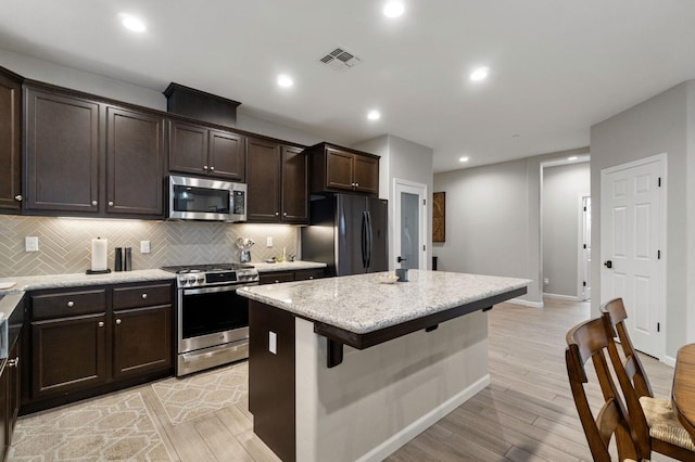 kitchen featuring light stone counters, light wood-type flooring, stainless steel appliances, and a kitchen island