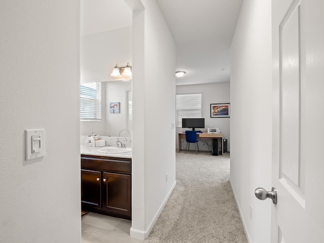 corridor featuring sink and light carpet