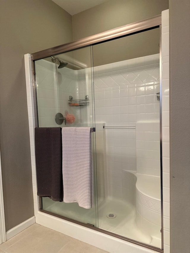 bathroom with a shower with door and tile patterned floors