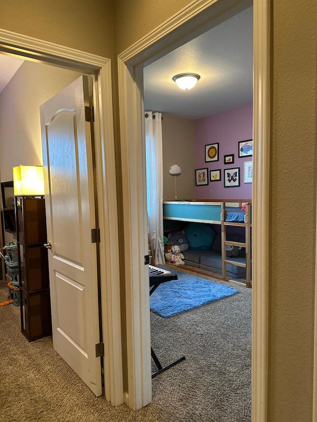 hall with carpet flooring and a textured ceiling