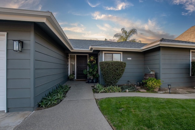 exterior entry at dusk featuring a lawn