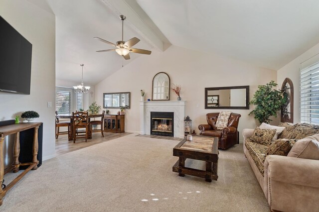 carpeted living room with beam ceiling, ceiling fan with notable chandelier, and high vaulted ceiling