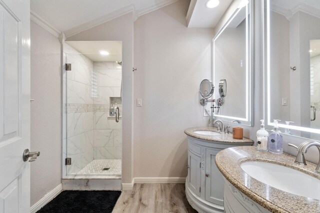 bathroom with vaulted ceiling, vanity, wood-type flooring, ornamental molding, and a shower with shower door