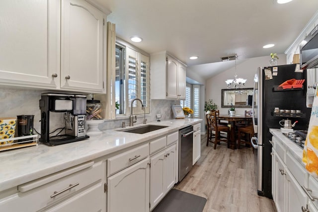 kitchen with appliances with stainless steel finishes, decorative light fixtures, white cabinetry, sink, and light hardwood / wood-style floors