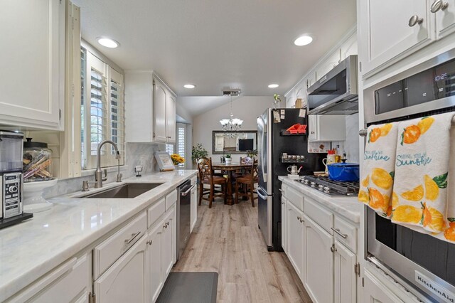 kitchen with stainless steel appliances, white cabinetry, sink, and decorative light fixtures