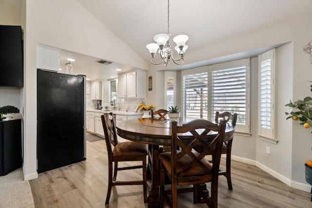 dining area featuring lofted ceiling, a chandelier, and light wood-type flooring