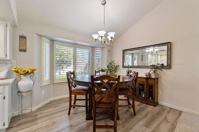 dining area featuring a notable chandelier, vaulted ceiling, and light wood-type flooring