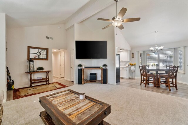 carpeted living room with ceiling fan with notable chandelier, beam ceiling, and high vaulted ceiling