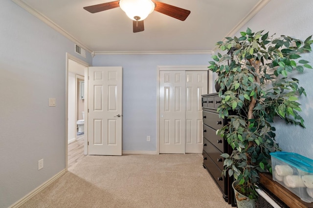 unfurnished bedroom featuring ceiling fan, ornamental molding, a closet, and light carpet