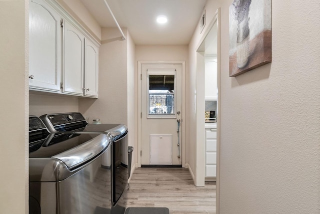 laundry room featuring cabinets, washing machine and clothes dryer, and light wood-type flooring