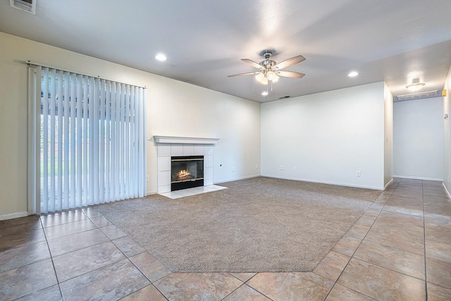 unfurnished living room with light colored carpet, a tile fireplace, and ceiling fan