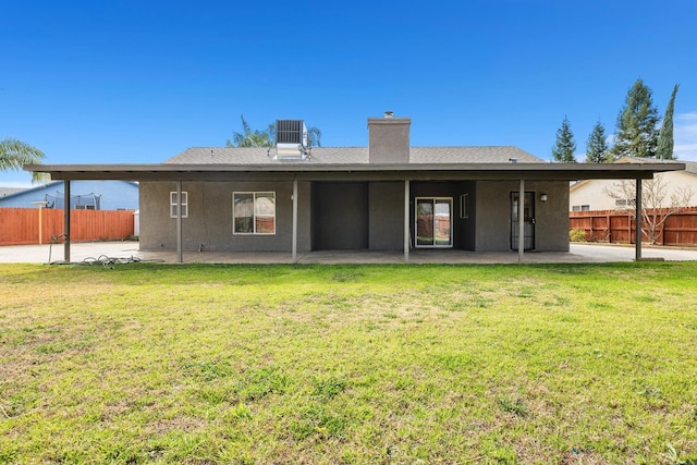 rear view of house featuring cooling unit, a patio, and a lawn