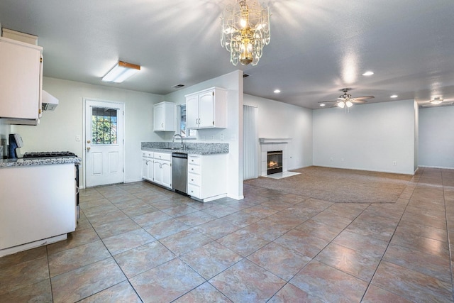 kitchen featuring sink, dishwasher, white cabinetry, ventilation hood, and a tiled fireplace