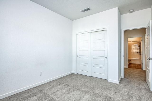 unfurnished bedroom with light colored carpet, a closet, and a textured ceiling