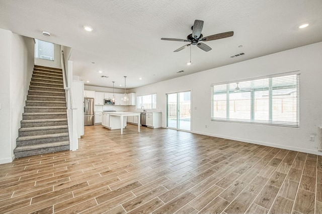 unfurnished living room featuring sink, a textured ceiling, light hardwood / wood-style flooring, and ceiling fan