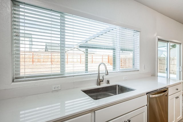 kitchen with dishwasher, sink, a wealth of natural light, and white cabinets