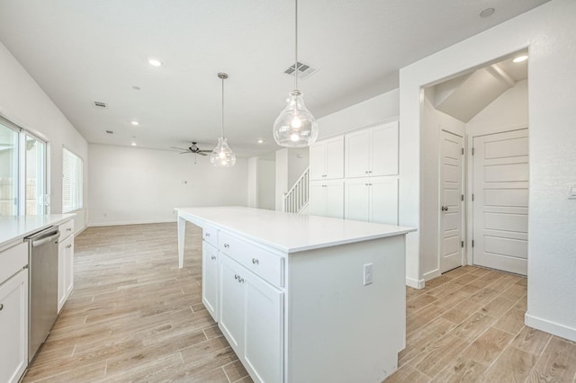 kitchen featuring ceiling fan, dishwasher, white cabinetry, a center island, and decorative light fixtures