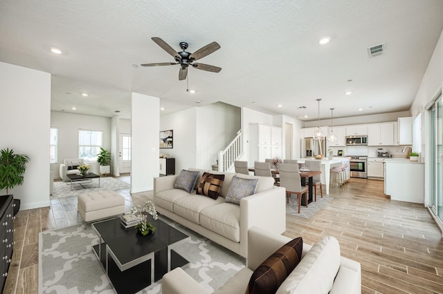 living room with ceiling fan, sink, and a textured ceiling