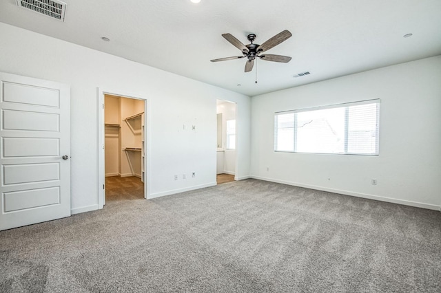 unfurnished bedroom with ensuite bathroom, carpet flooring, a walk in closet, ceiling fan, and a closet