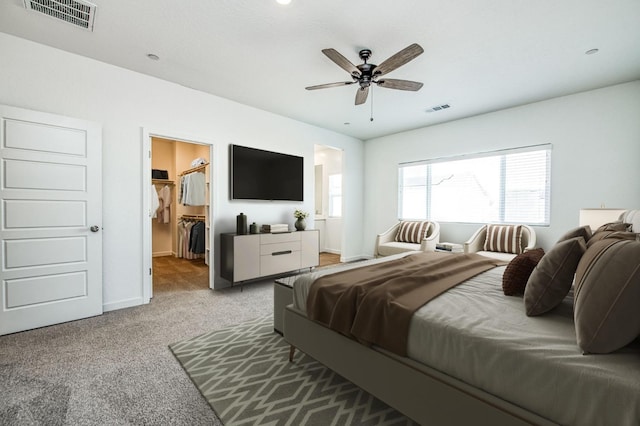 bedroom featuring a spacious closet, light colored carpet, and ceiling fan