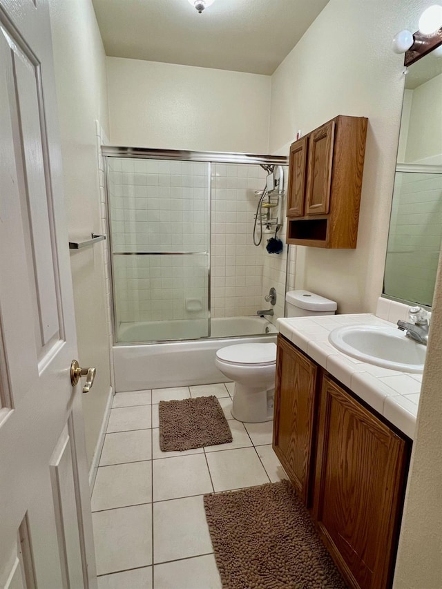 full bathroom with tile patterned flooring, bath / shower combo with glass door, vanity, and toilet