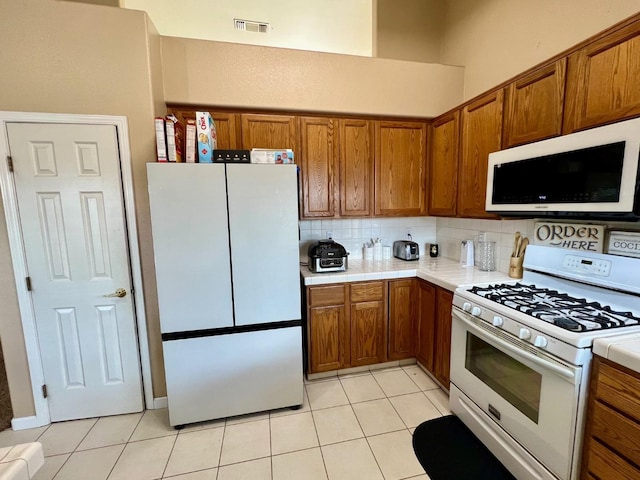 kitchen with white appliances, decorative backsplash, and light tile patterned floors