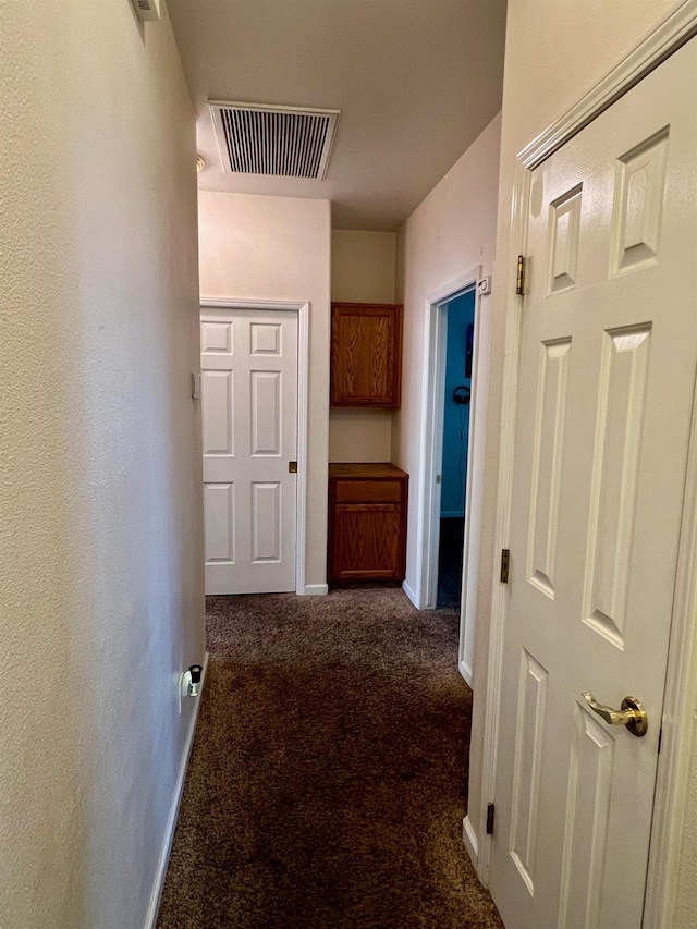 hall with dark colored carpet