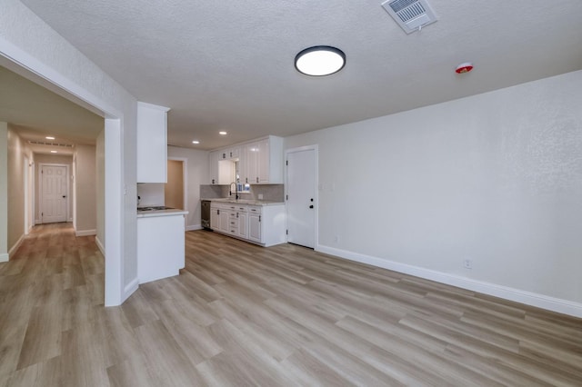 kitchen featuring sink, a textured ceiling, light hardwood / wood-style flooring, and white cabinets