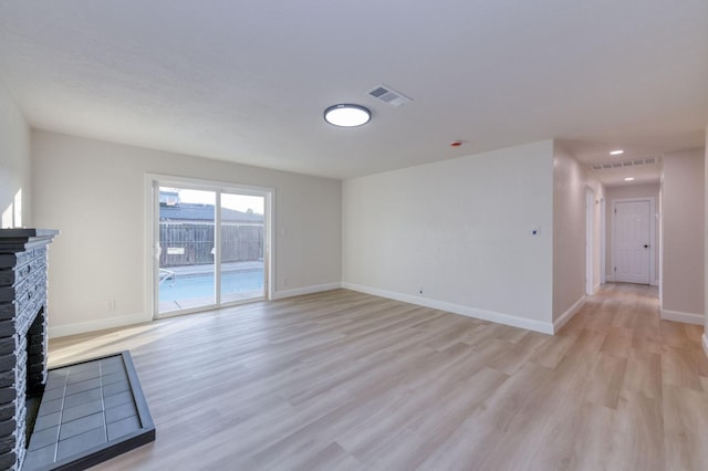 unfurnished living room with a brick fireplace and light wood-type flooring