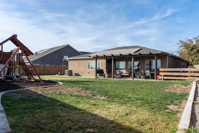 back of property with a playground, a patio, a lawn, and central air condition unit