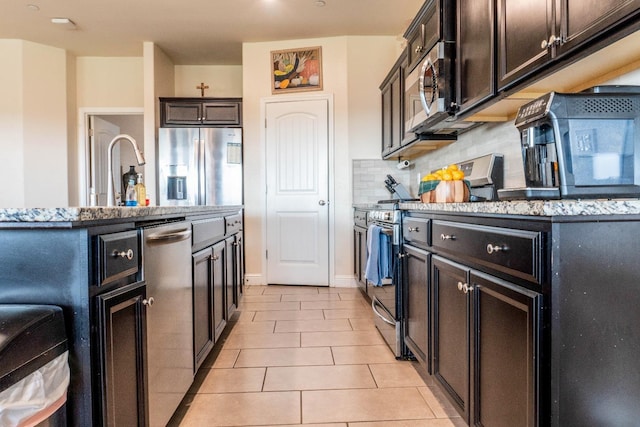 kitchen featuring light tile patterned floors, sink, a kitchen island with sink, stainless steel appliances, and tasteful backsplash