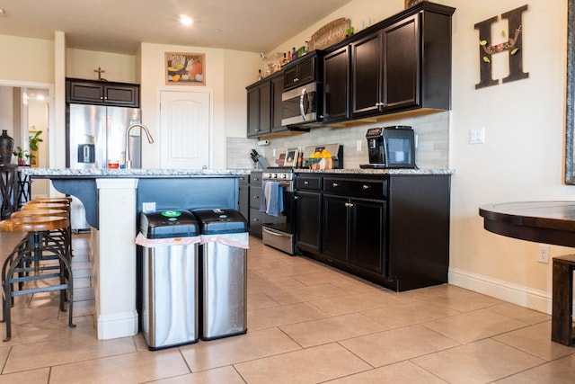 kitchen with a center island with sink, light stone countertops, and stainless steel appliances