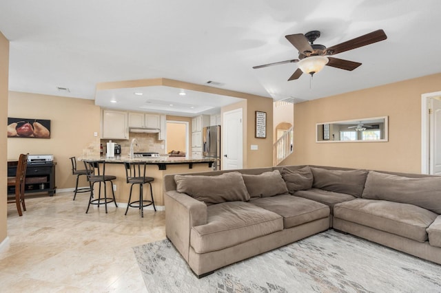 living room with a raised ceiling and ceiling fan