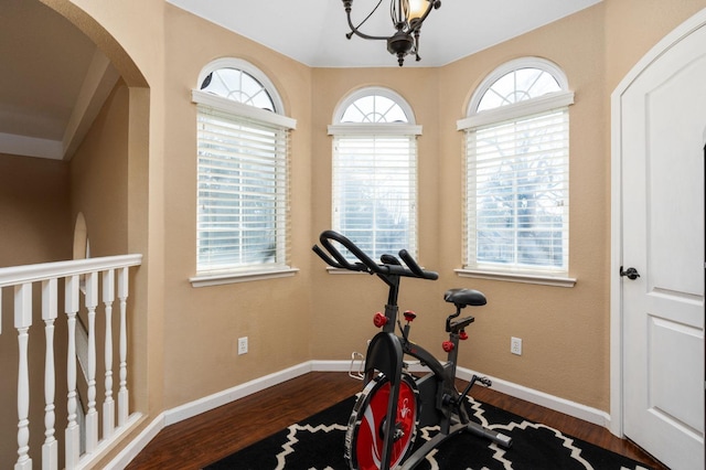 exercise area featuring dark wood-type flooring and an inviting chandelier