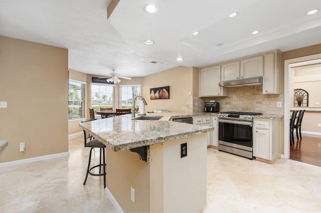 kitchen featuring sink, backsplash, a kitchen breakfast bar, stainless steel appliances, and kitchen peninsula