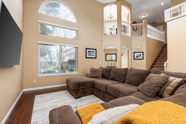 living room with a notable chandelier, a towering ceiling, and wood-type flooring