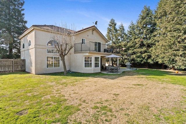 back of property featuring a balcony, a lawn, and a patio area