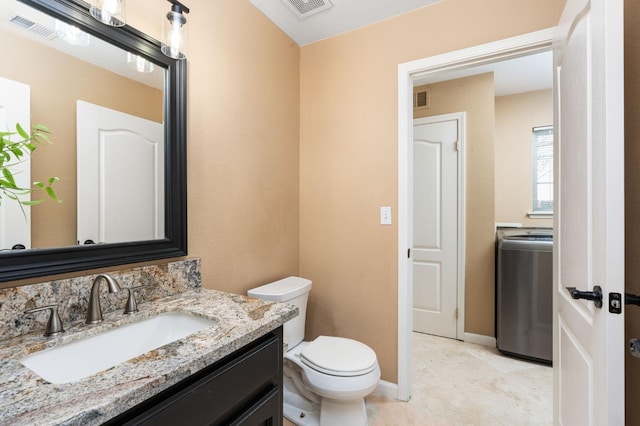 bathroom featuring vanity, washer / clothes dryer, tile patterned flooring, and toilet