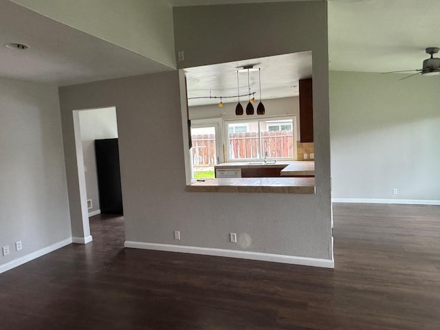 interior space featuring ceiling fan, a sink, dark wood finished floors, and baseboards