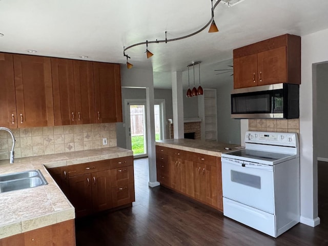 kitchen featuring dark wood-style flooring, white range with electric cooktop, stainless steel microwave, decorative backsplash, and a sink