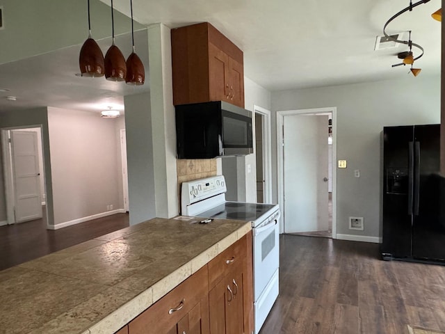 kitchen featuring white electric range, black fridge, brown cabinetry, stainless steel microwave, and dark wood finished floors